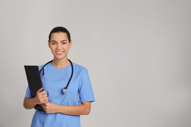 Photo of Portrait of young medical assistant with stethoscope and clipboard on color background. Space for text