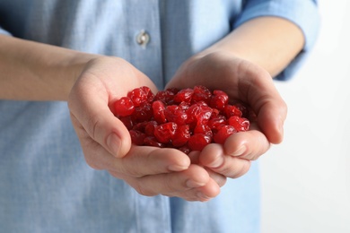 Woman holding handful of tasty cherries on light background, closeup. Dried fruits as healthy food