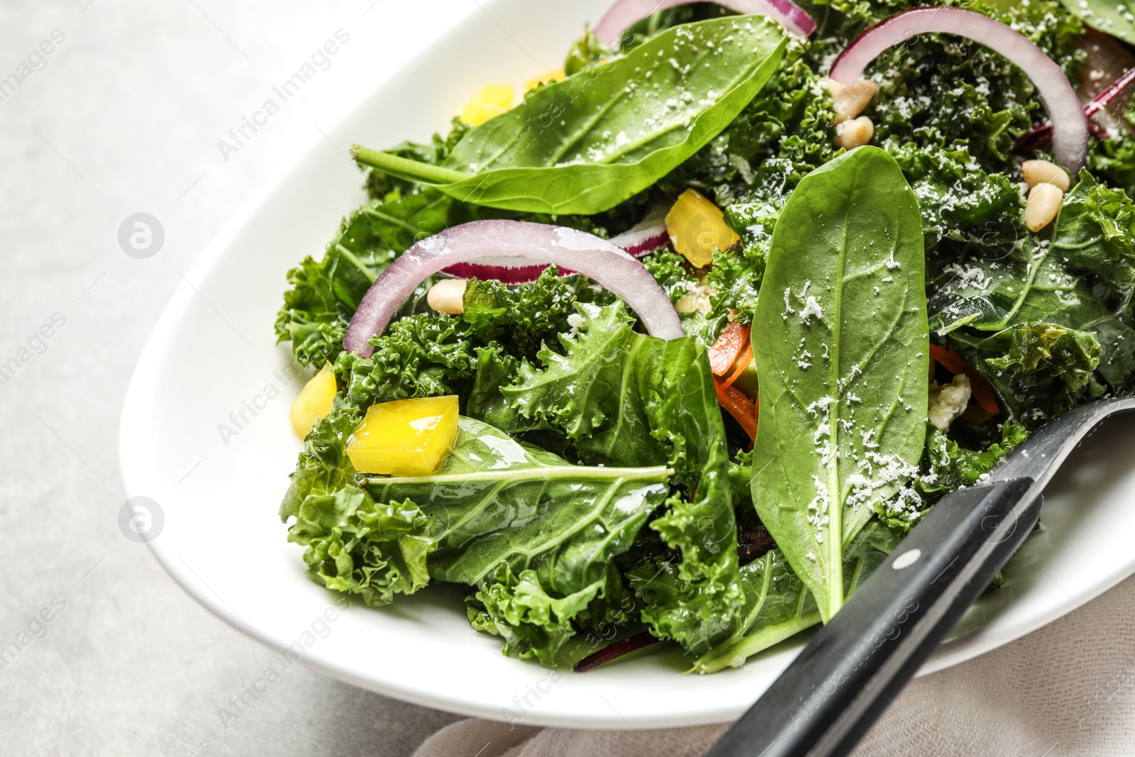 Photo of Tasty fresh kale salad on grey table, closeup