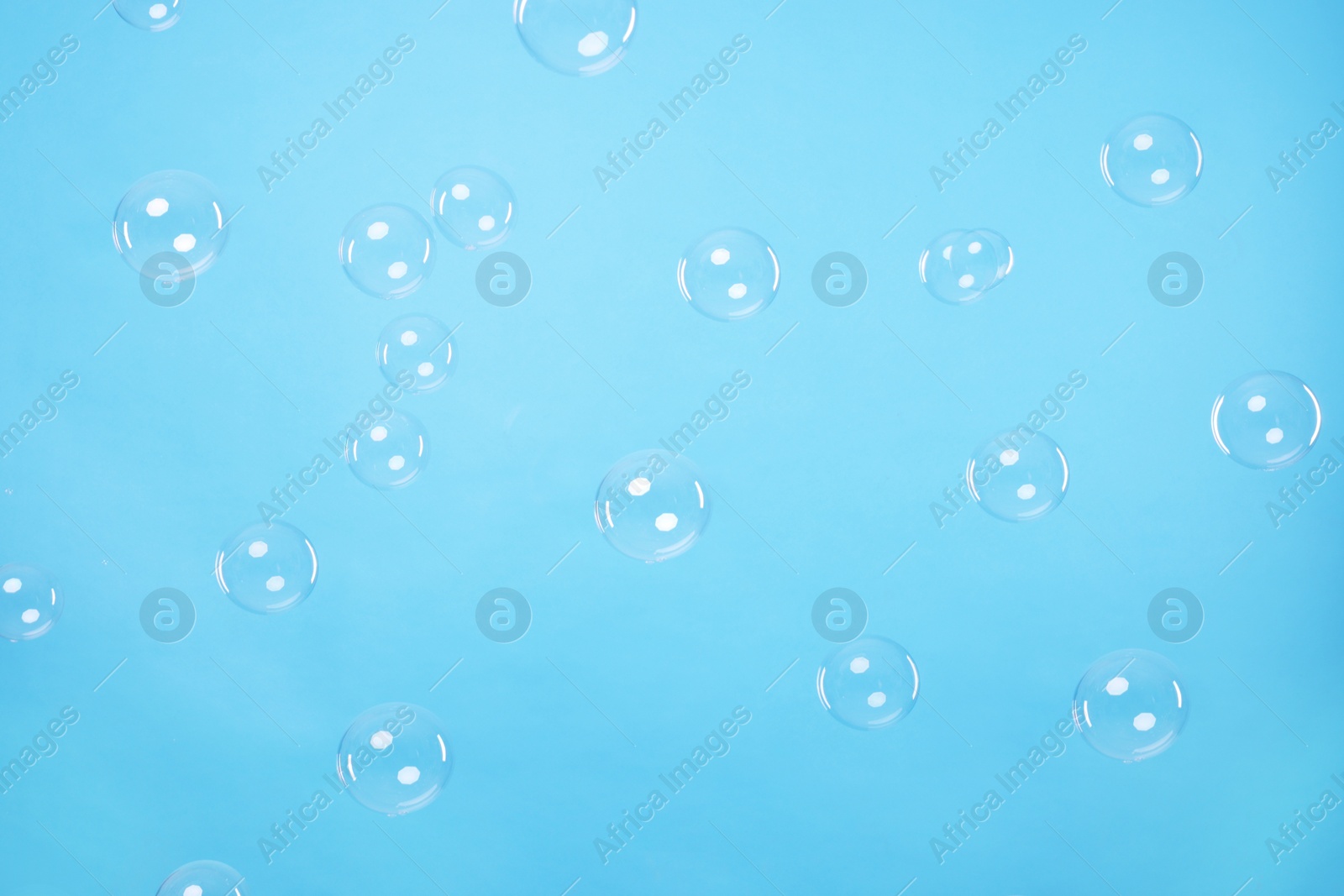 Photo of Many beautiful soap bubbles on light blue background