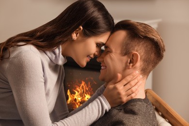 Happy lovely couple spending time together near fireplace indoors