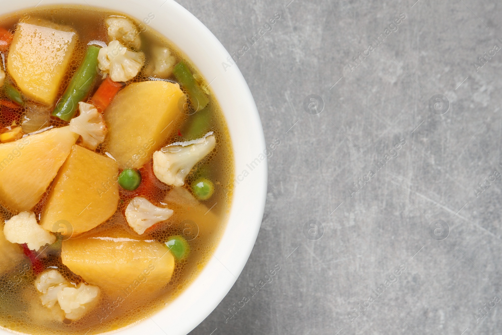 Photo of Bowl of delicious turnip soup on light grey table, top view. Space for text