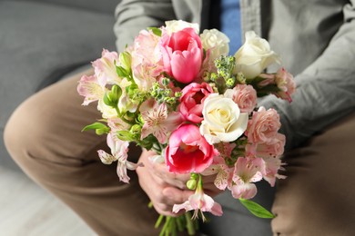 Man holding bouquet of beautiful flowers indoors, closeup