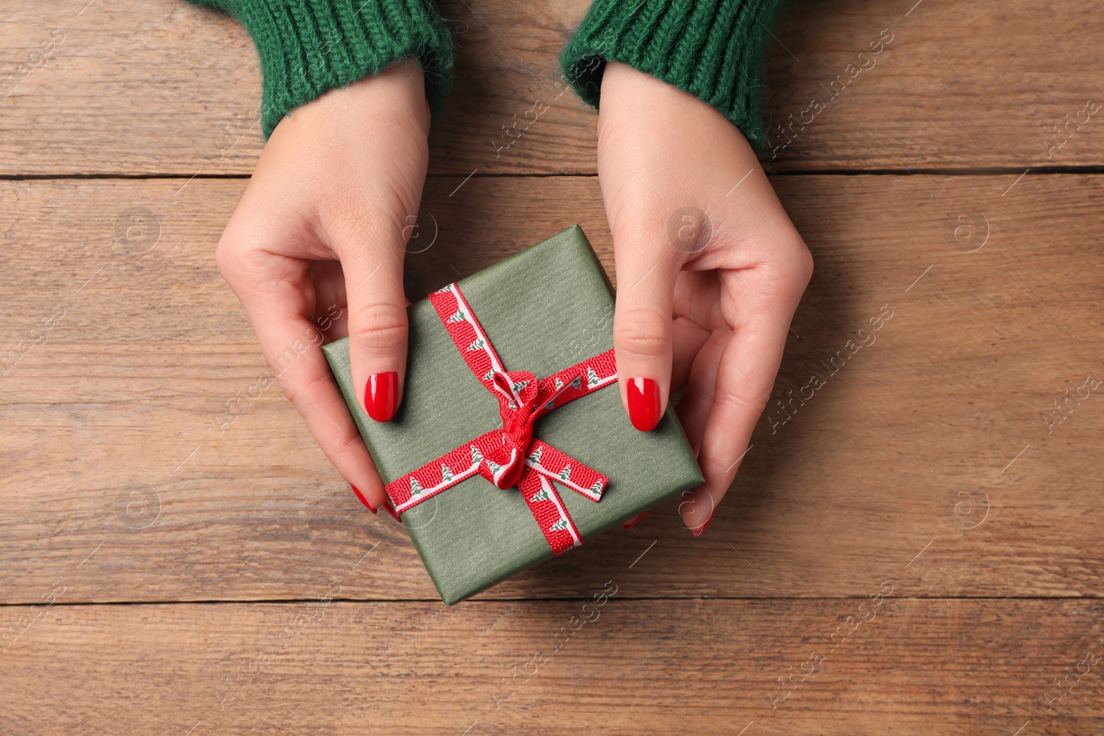 Photo of Christmas present. Woman with gift box at wooden table, top view