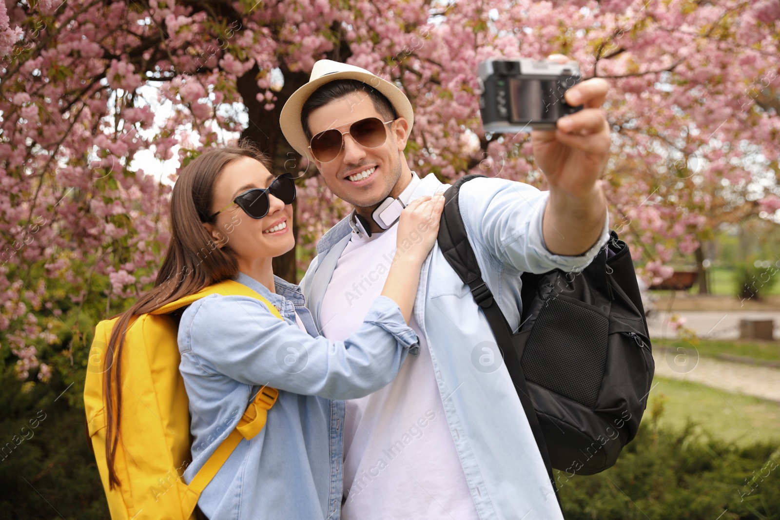 Photo of Happy couple of tourists taking selfie in blossoming park on spring day