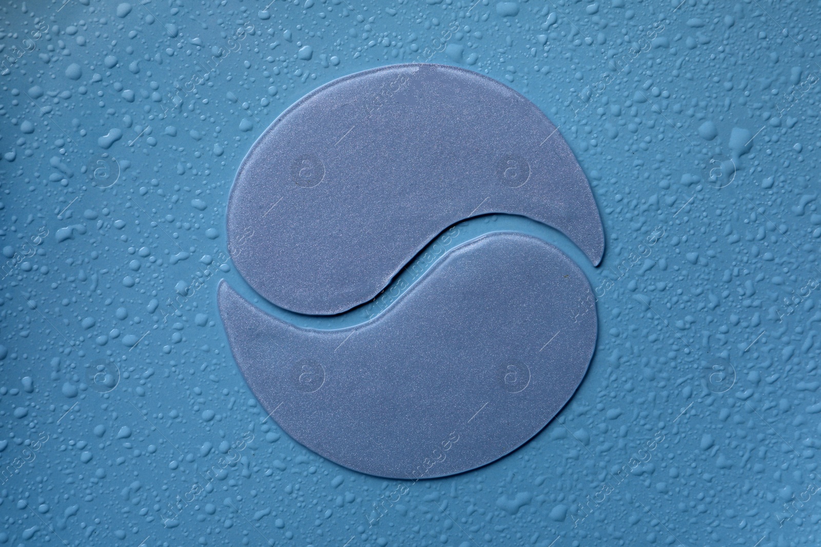 Photo of Under eye patches on blue wet background, flat lay. Cosmetic product