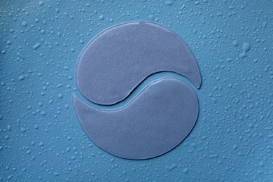 Photo of Under eye patches on blue wet background, flat lay. Cosmetic product