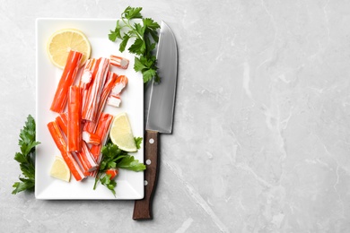 Photo of Delicious crab sticks served on light grey marble table, flat lay. Space for text