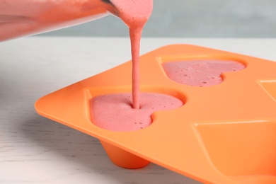 Photo of Pouring smoothie into ice cube tray on table, closeup