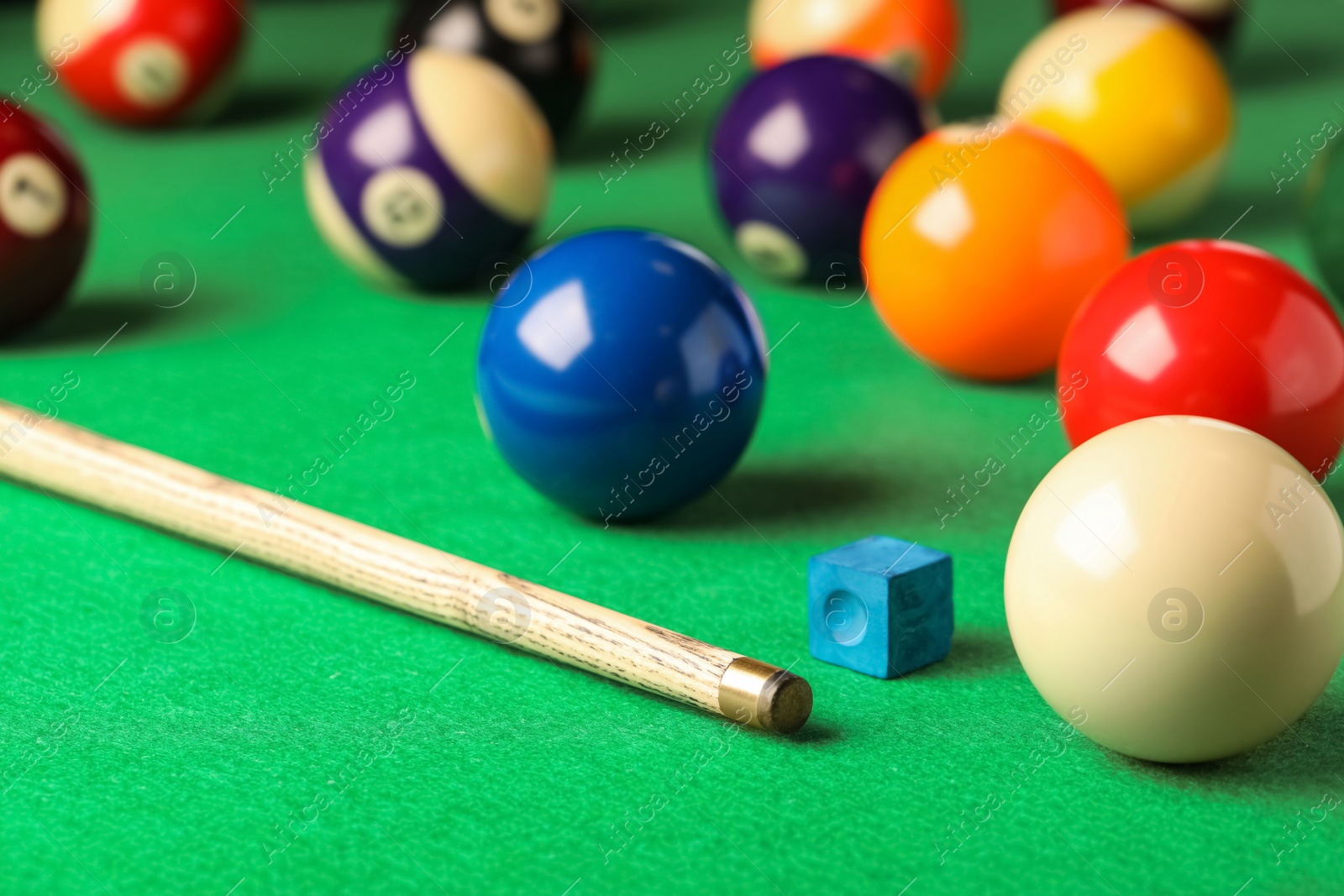Photo of Many colorful billiard balls, cue and chalk on green table. Space for text