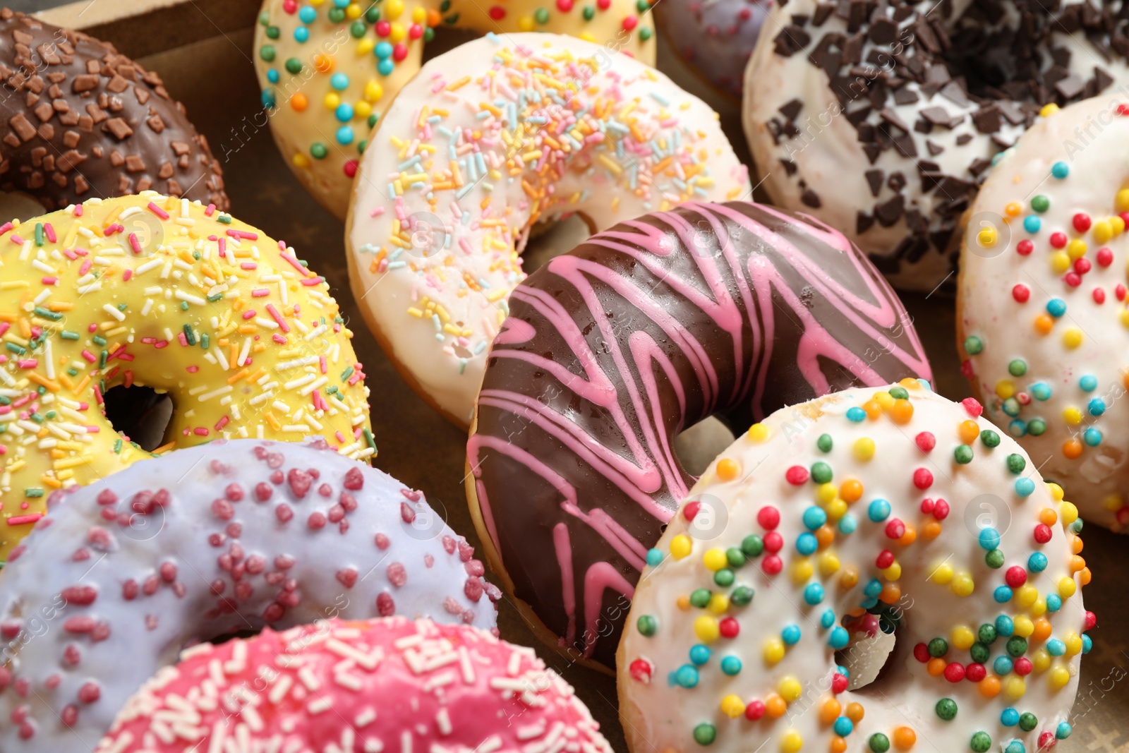 Photo of Yummy glazed donuts with sprinkles, closeup view