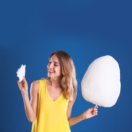 Photo of Happy young woman with cotton candy on blue background