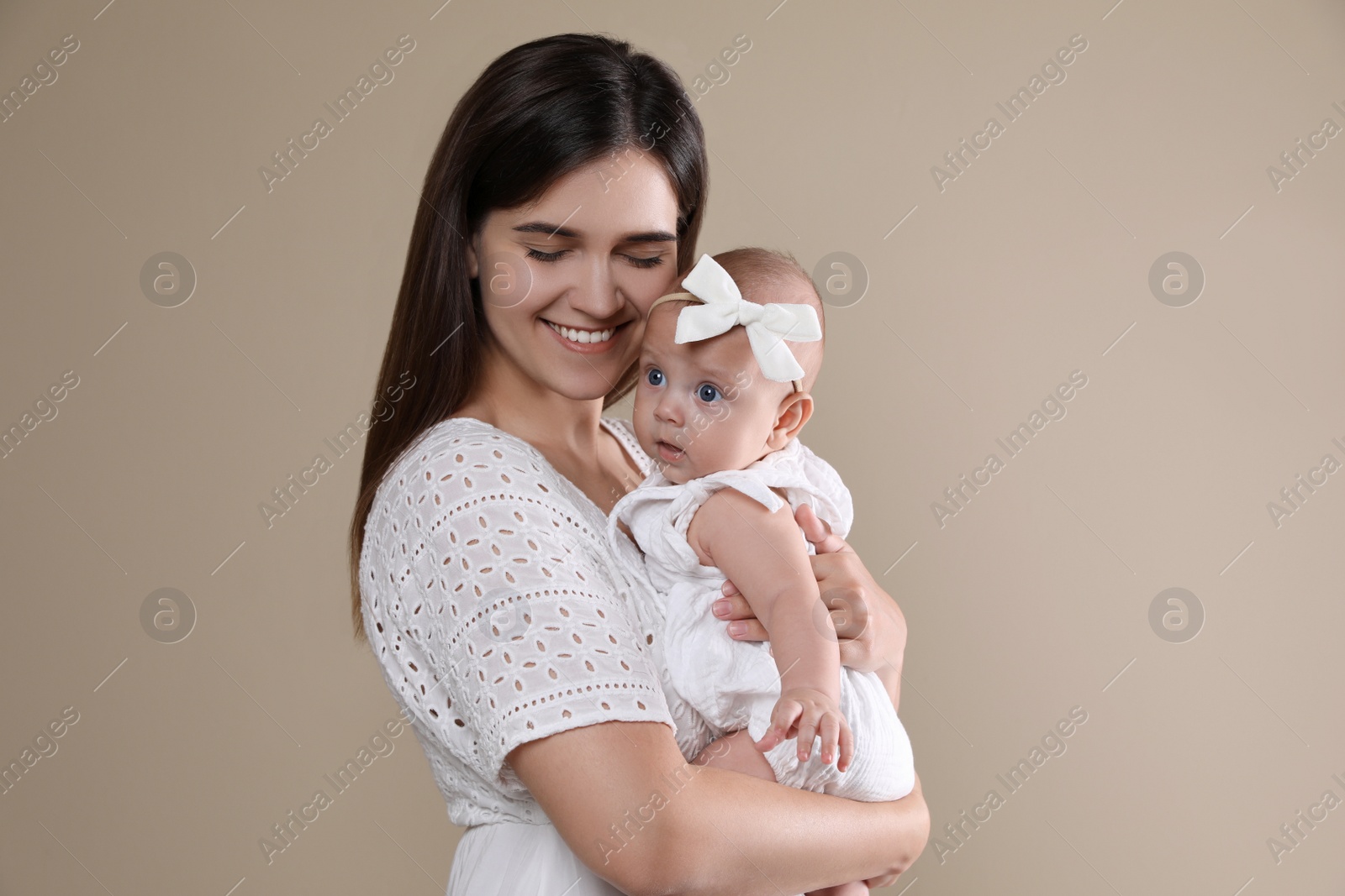 Photo of Beautiful mother with her cute baby on beige background