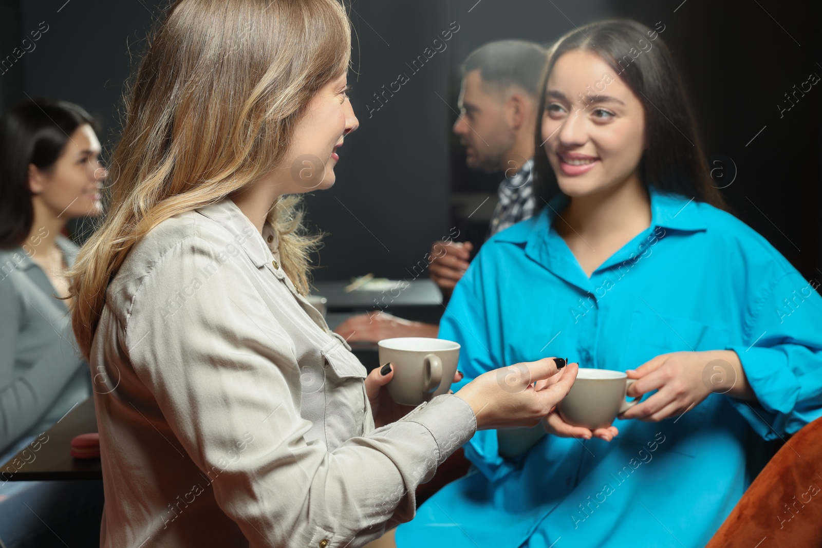 Photo of Young women with coffee spending time together in cafe