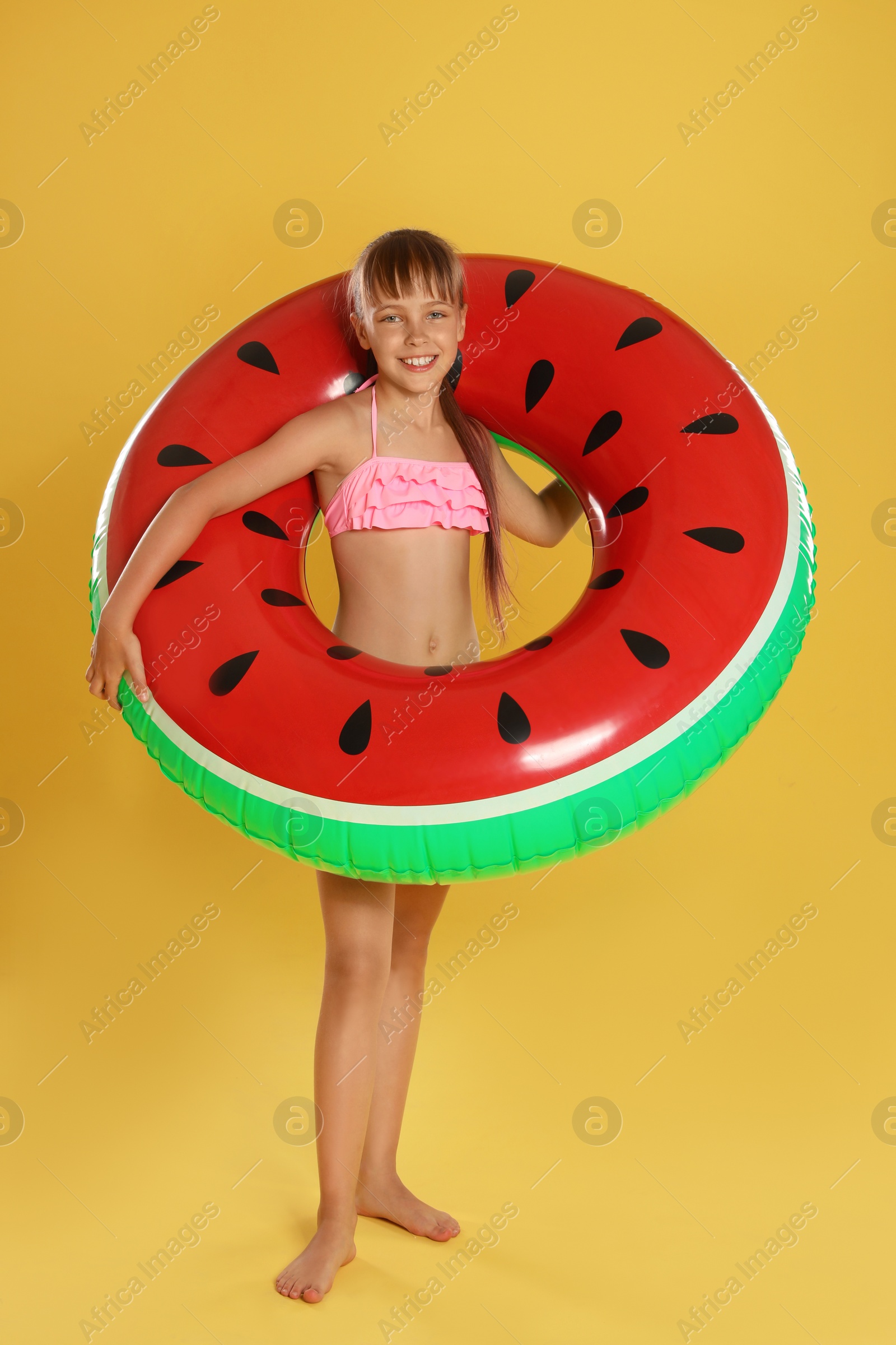 Photo of Cute little girl with bright inflatable ring on yellow background