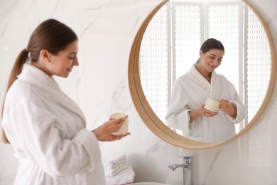 Photo of Young pregnant woman with cosmetic product in bathroom