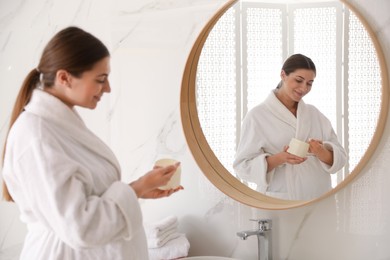 Young pregnant woman with cosmetic product in bathroom