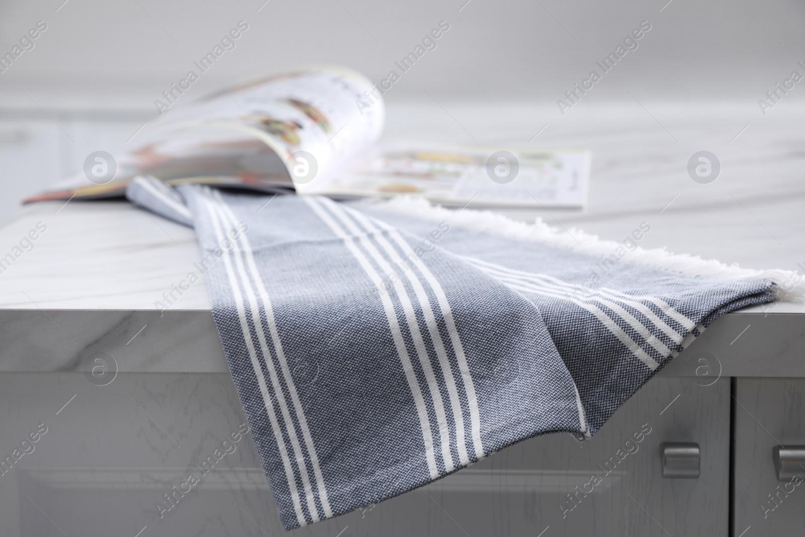 Photo of Kitchen towel and magazine on white marble table