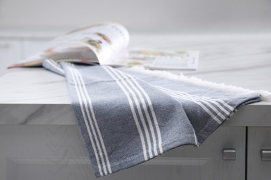 Photo of Kitchen towel and magazine on white marble table