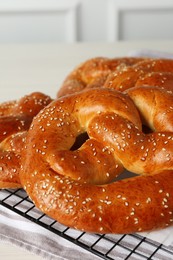Photo of Tasty freshly baked pretzels on cooling grid, closeup view