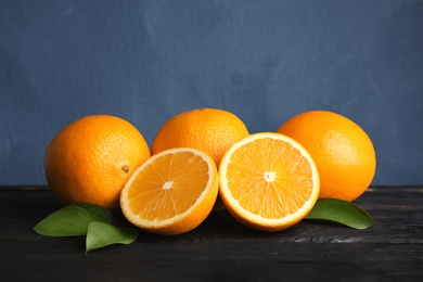 Fresh oranges with leaves on wooden table