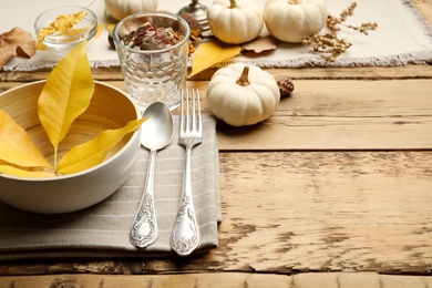 Seasonal table setting with pumpkins and other autumn decor on wooden background. Space for text