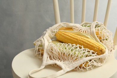 Photo of Bag of corn cobs on chair against grey background