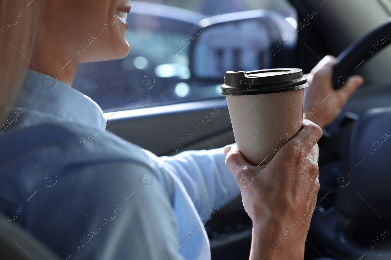 Photo of Coffee to go. Woman with paper cup of drink driving her car, closeup