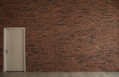 Photo of Empty room with brick wall and white door