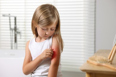 Photo of Suffering from allergy. Little girl scratching her arm in bathroom, space for text