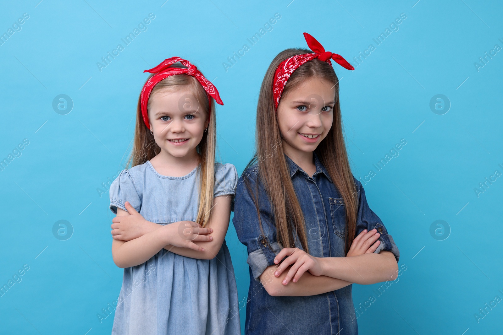 Photo of Cute little sisters on light blue background