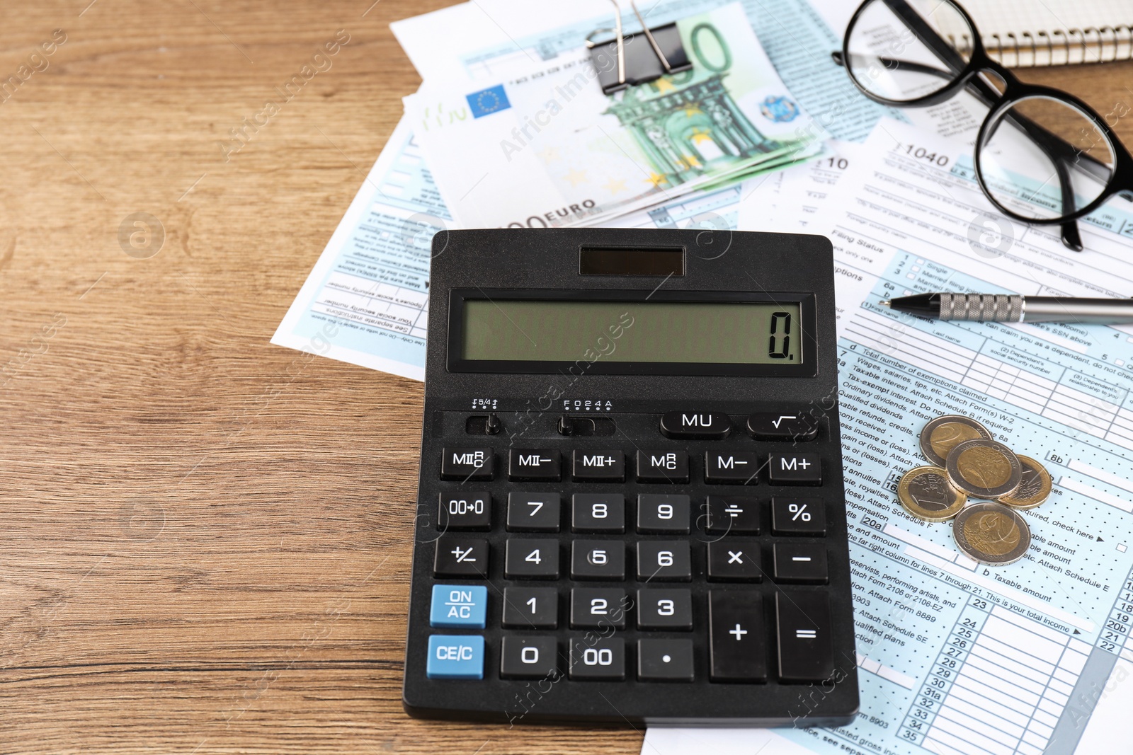 Photo of Tax accounting. Calculator, documents, money, glasses and pen on wooden table, closeup. Space for text