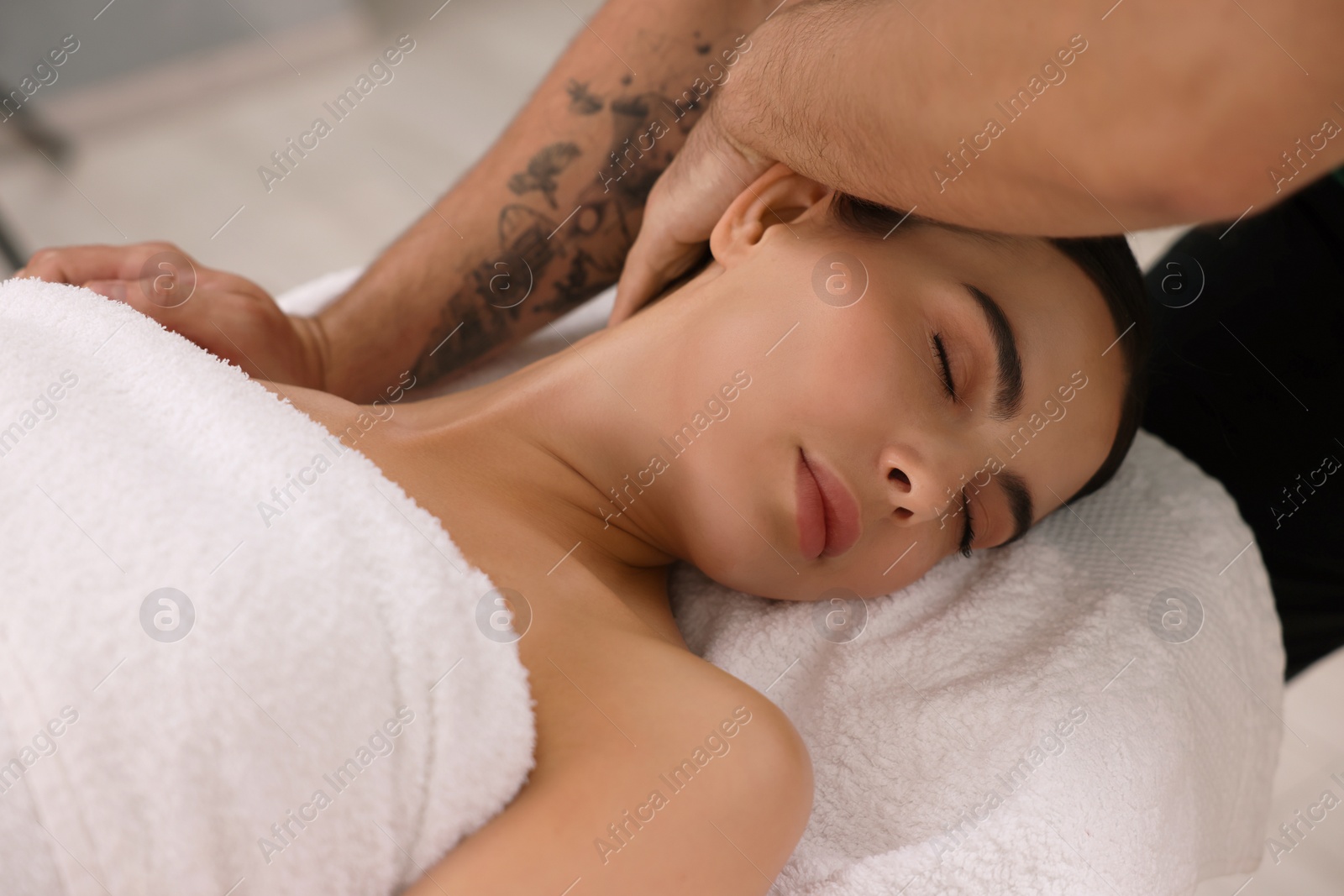 Photo of Woman receiving professional neck massage on couch indoors