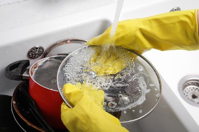 Photo of Woman washing glass lid in kitchen sink, closeup