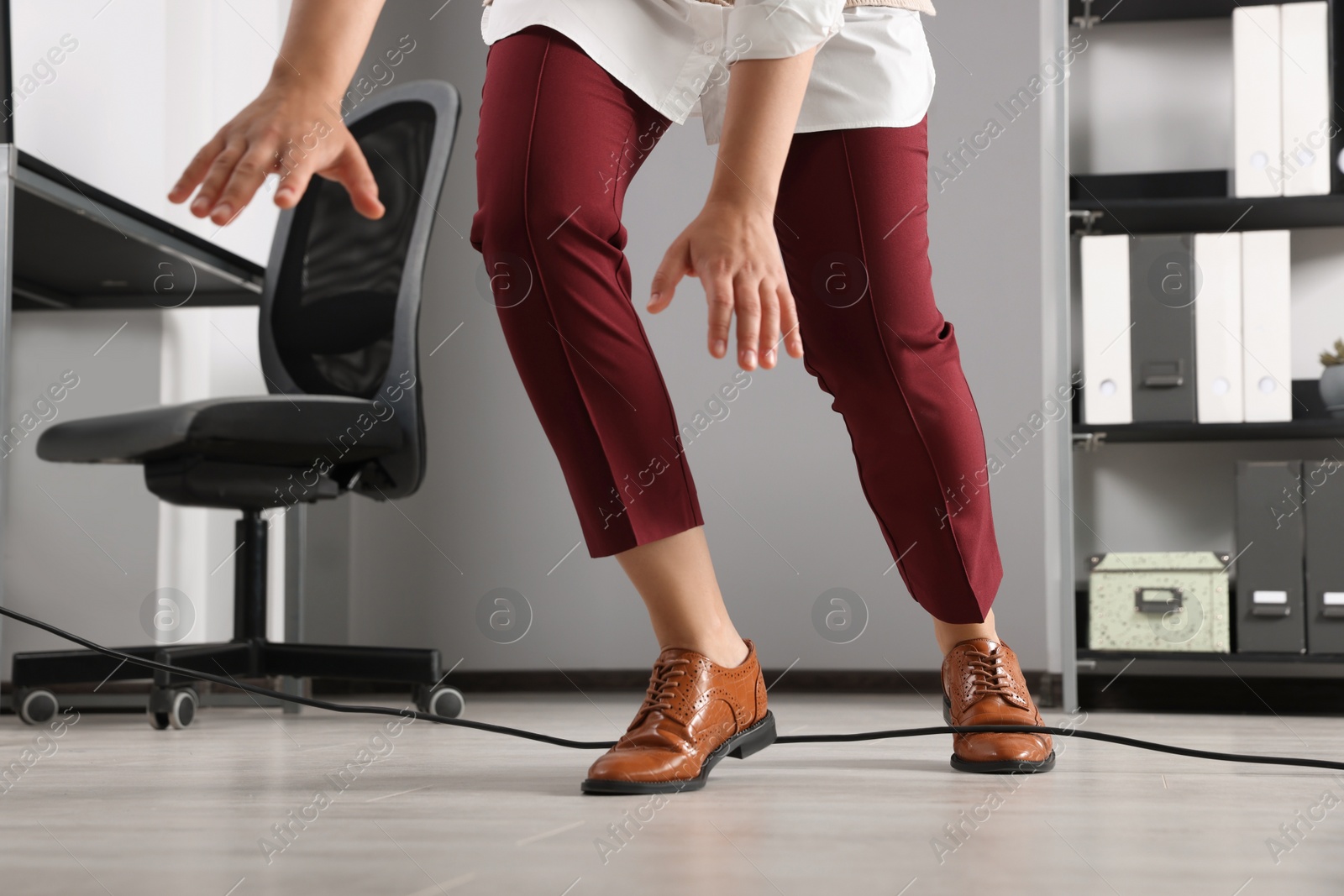 Photo of Woman tripping over cable in office, closeup