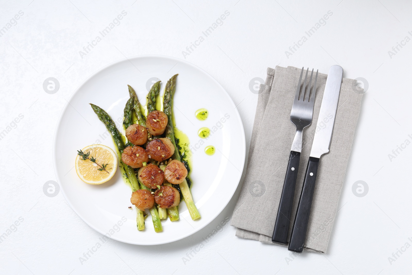 Photo of Delicious fried scallops with asparagus, lemon and thyme served on white table, flat lay