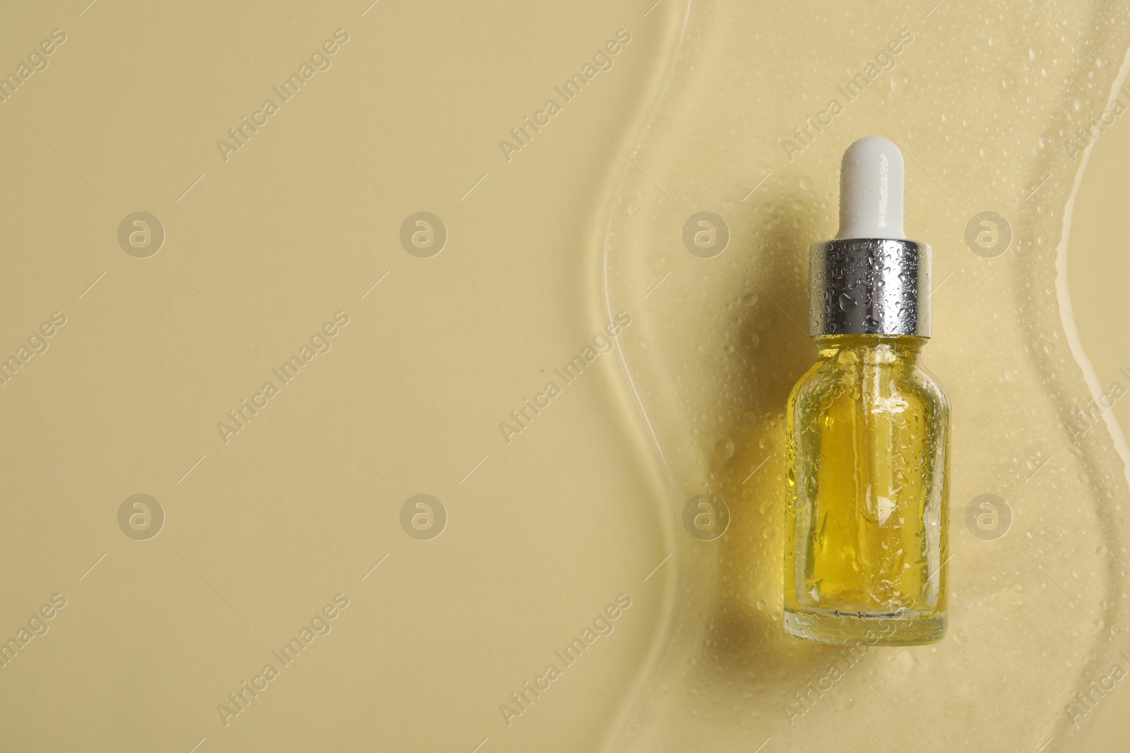 Photo of Bottle of cosmetic serum on beige background, top view. Space for text