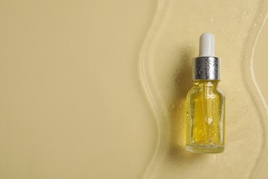 Bottle of cosmetic serum on beige background, top view. Space for text