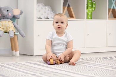 Children toys. Cute little boy playing with wooden cars on rug at home