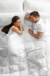 Lovely young couple sleeping in large bed, above view