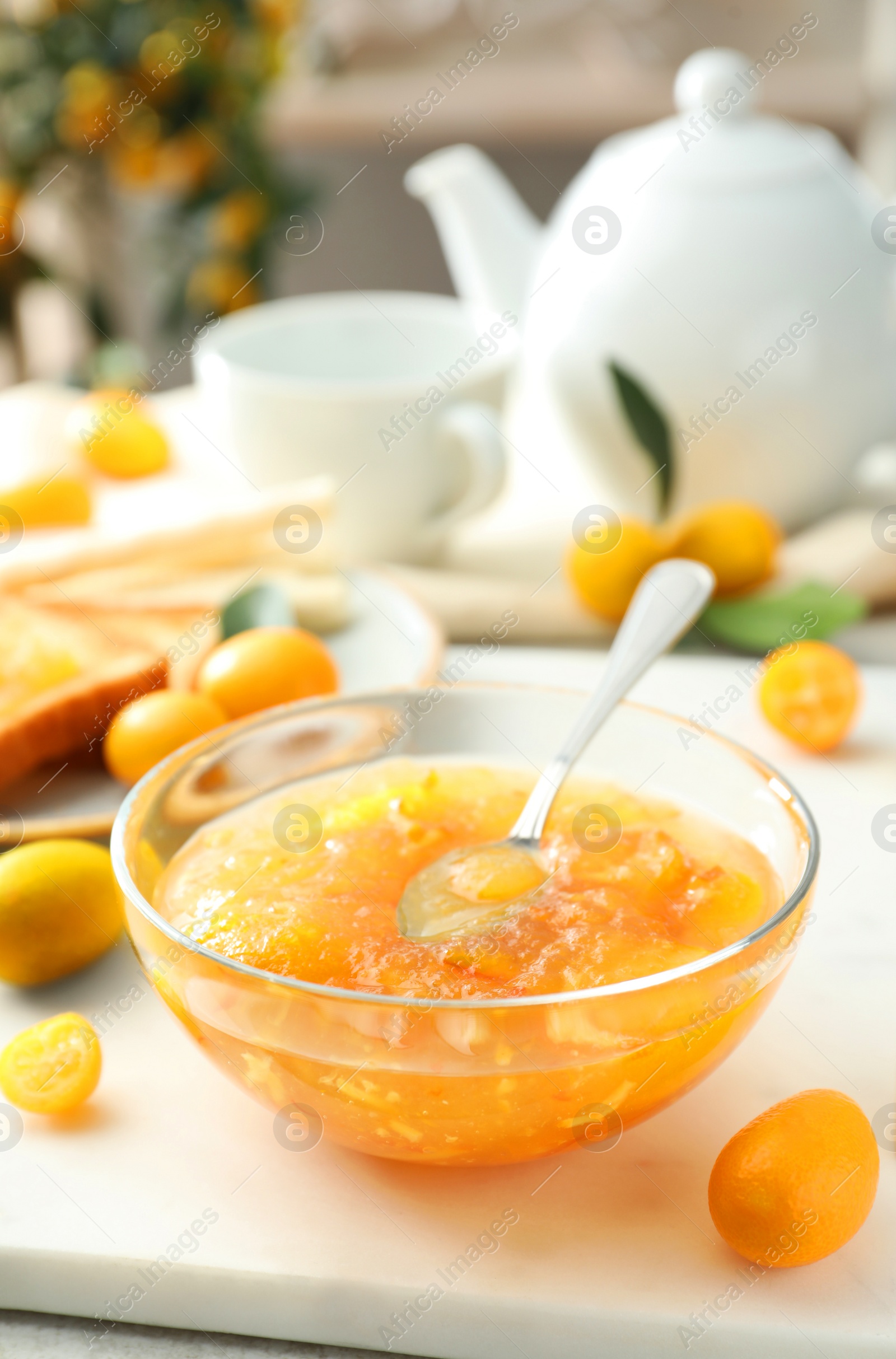 Photo of Delicious kumquat jam in glass bowl on white board