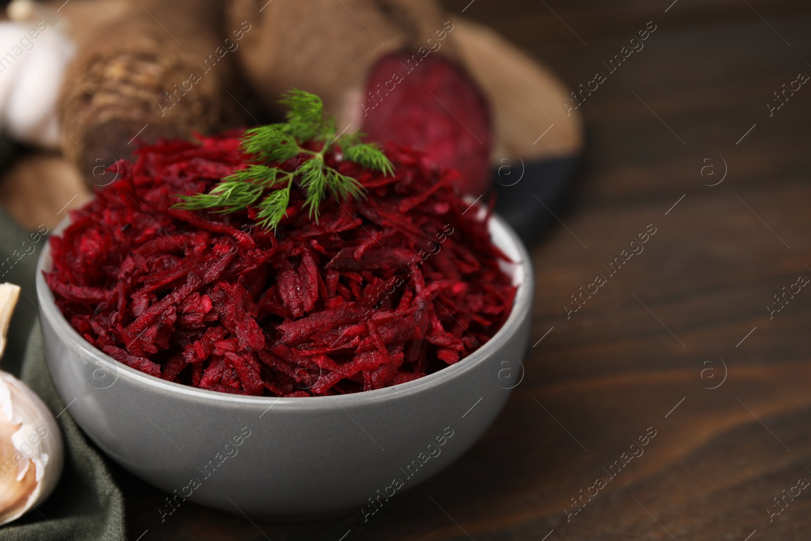 Photo of Grated red beet and dill in bowl on table, closeup