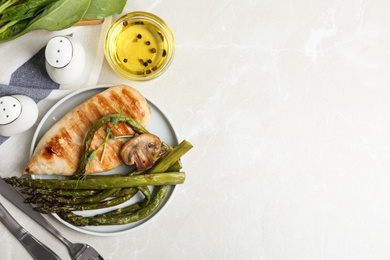 Photo of Tasty grilled chicken fillet served with asparagus on light grey marble table, flat lay. Space for text