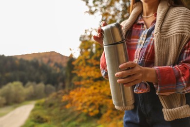 Photo of Woman with metallic thermos outdoors, closeup. Space for text