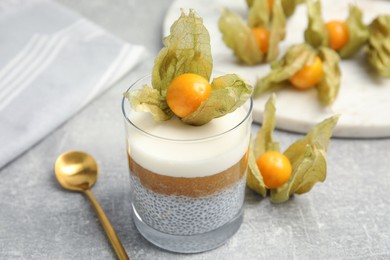 Delicious chia pudding decorated with physalis on light grey table