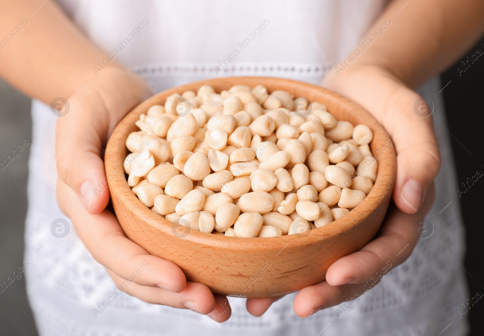 Photo of Woman holding bowl with shelled peanuts, closeup