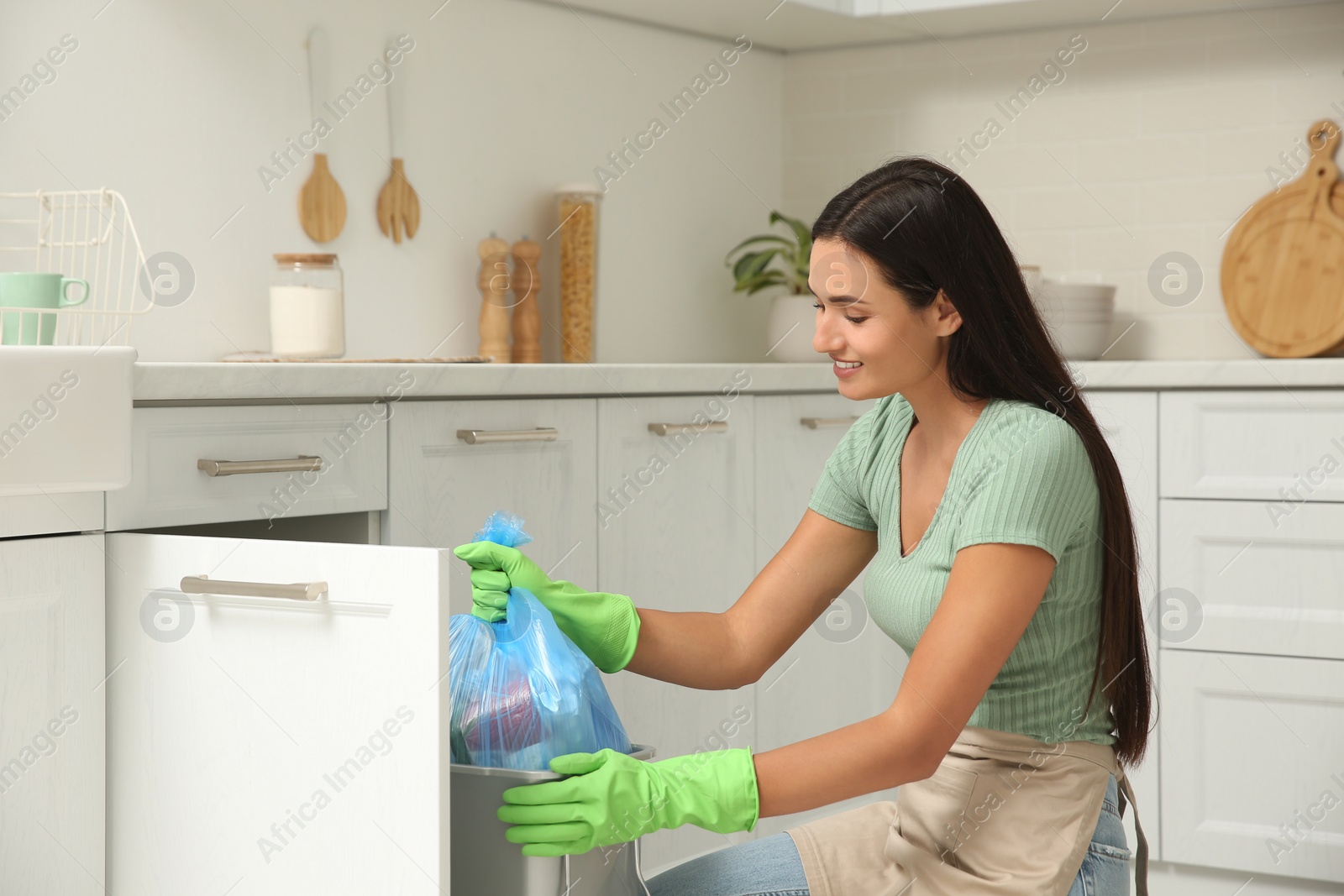 Photo of Woman taking garbage bag out of bin at home