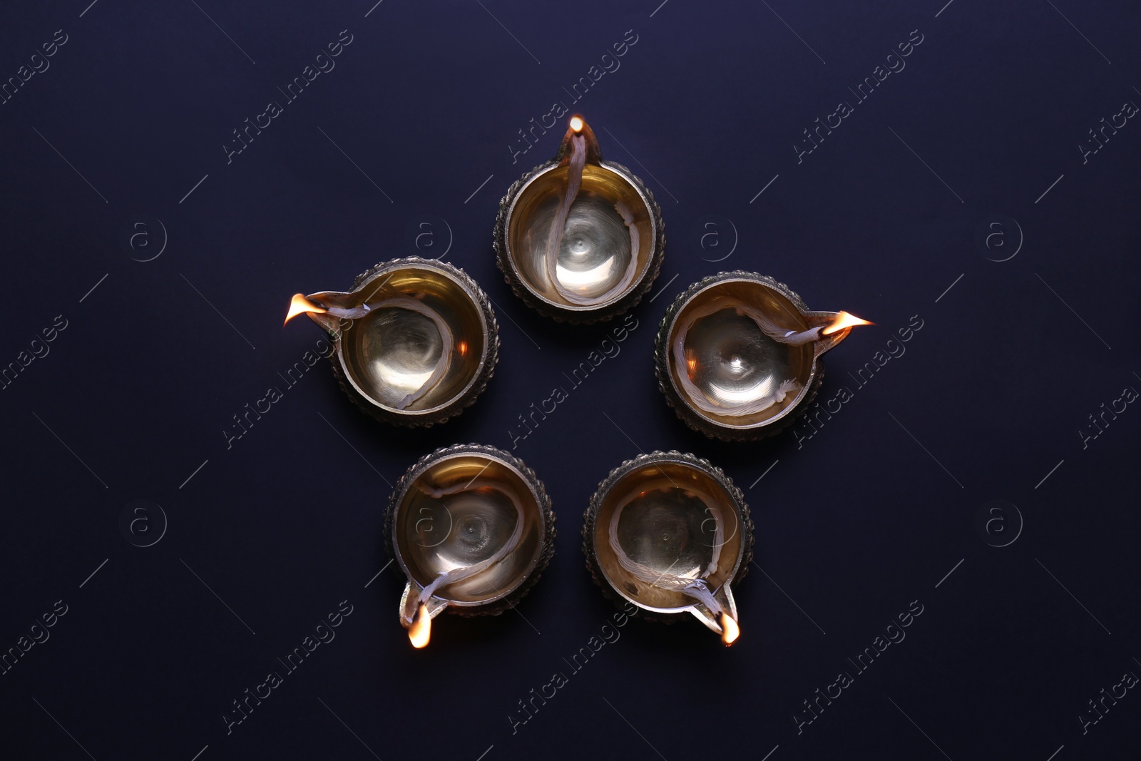 Photo of Lit diyas on dark background, flat lay. Diwali lamps