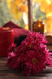 Photo of Beautiful chrysanthemum flowers on wooden table indoors, closeup