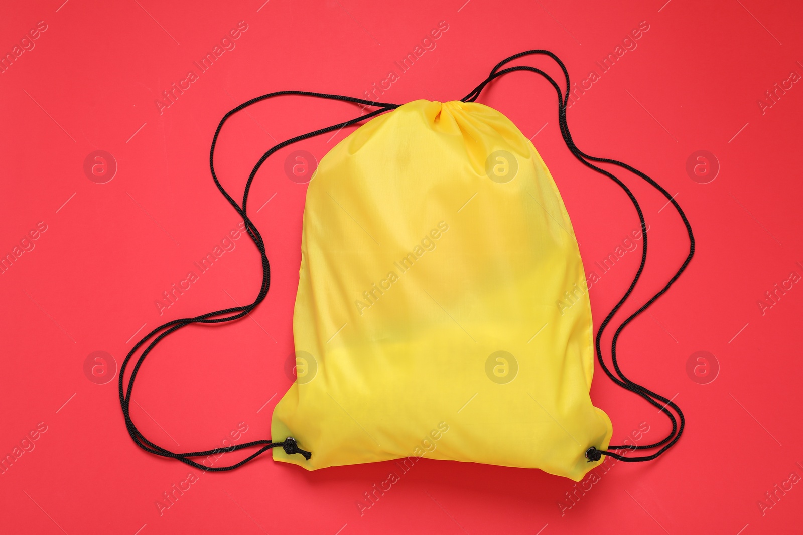 Photo of Yellow drawstring bag on red background, top view